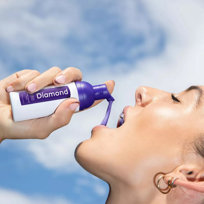 Frau mit Diamond Smile Lila Zahnbleaching Farbkorrektur Schaum in der Hand