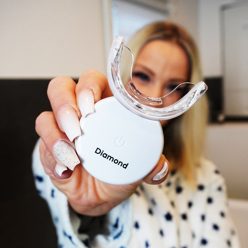 Frau mit Diamond Smile Lila Farbkorrektur Zahnaufhellung Set - Lila Bleaching Set in der Hand